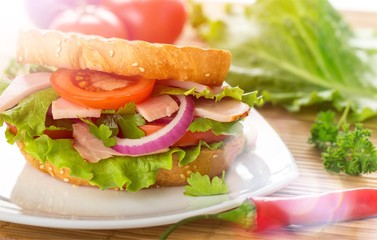 Fresh sandwich with ham and vegetables on wooden table
