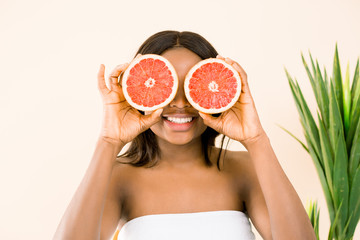 Beauty african woman with orange citrus grapefruit cover eyes with healthy skin body, isolated over white background. Attractive fresh vitamin. Studio shot.