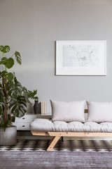 Silver abstract painting on grey wall above scandinavian futon