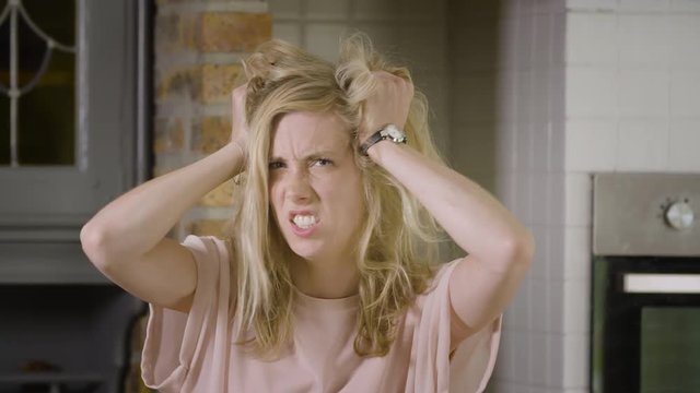 Beautiful blond woman going crazy messing up her hair looking at the camera