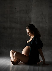 Beautiful young pregnant happy mother woman posing in underwear on dark 