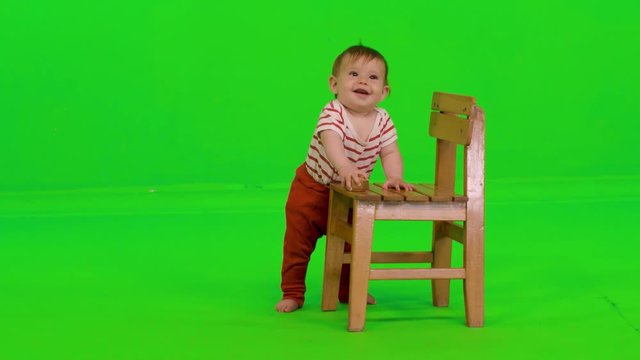 A cute baby girl plays with a toy, drops it, struggle and succeed in reaching to it, over a green screen.
