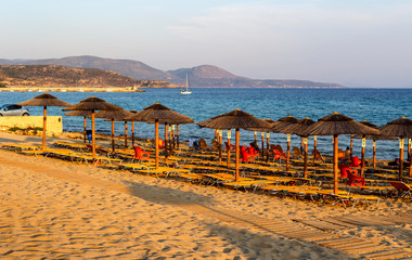 Sandy beach with sunbeds and umbrellas on an summer evening (Peloponnese, Greece)