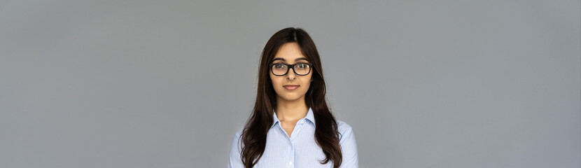 Indian young business woman wear blue shirt looking at camera isolated on grey studio background...
