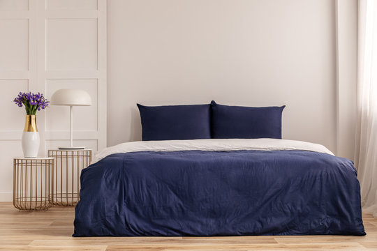 Simple navy blue and white bedroom interior with cozy bed with pillows and duvet