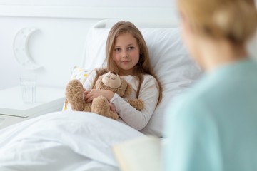 Girl in the hospital holding a teddy bear