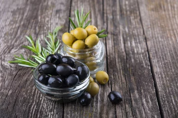Foto op Plexiglas black and green olives in bowls, rosemary sprigs on wooden background. Organic food, healthy nutrition © Vladyslava
