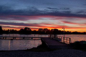 Piękny zachód słońca nad jeziorem Kalwa na Mazurach w Polsce., na pierwszym planie pomost na...