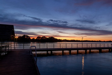 Piękny zachód słońca nad jeziorem Kalwa na Mazurach w Polsce., na pierwszym planie pomost na jeziorze. - obrazy, fototapety, plakaty