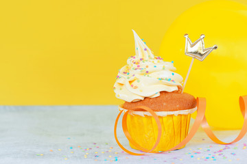 Bright birthday cupcake with decoration on yellow