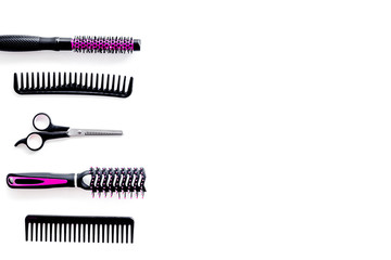 Combs, sciccors and pink hairdresser tools in beauty salon work desk on white background top view space for text