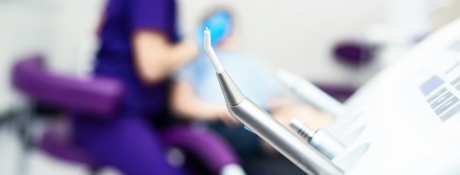 Blurred dental office. Tools are in the foreground. A doctor examines the patient