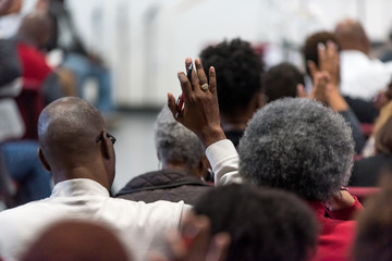 African American Man in a White Suit at Church with His Hand Raised
