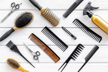 Combs, spray and hairdresser tools in beauty salon work desk on white wooden background top view pattern