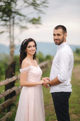 Fototapeta premium Lovestory of beautiful couple in the mountains, Handsome bearded man with beautiful and charming woman. Couple stand in front of beautiful tree