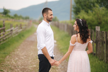 Handsome man leads his bride to beautiful Carpathian mountains. Happy wedding couple. Back view