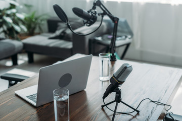 workspace with microphones, laptop and glasses of water in broadcasting studio