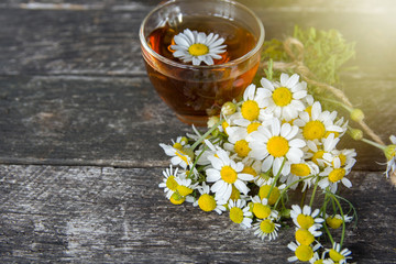 cup of herbal chamomile tea with fresh daisy flowers on wooden background. doctor treatment and...