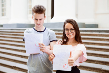 Two students with test results. Happy female student have received excellent A grade, but her male...