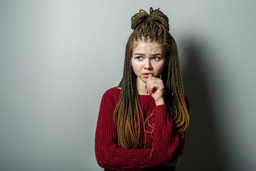 Close up shot of scary emotional young pretty caucasian teenage girl with african braids and problem skin and in maroon sweater.