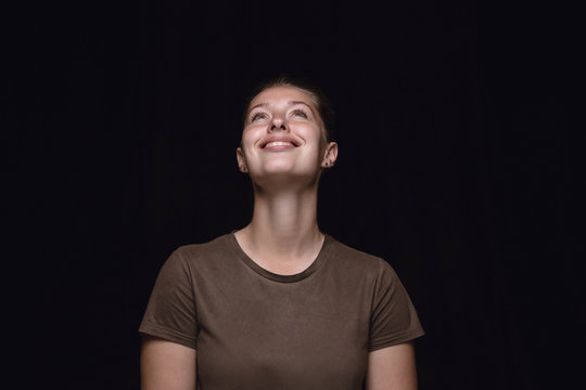 Close Up Portrait Of Young Woman Isolated On Black Studio Background. Photoshot Of Real Emotions Of Female Model. Dreaming And Smiling, Hopeful And Happy. Facial Expression, Human Emotions Concept.