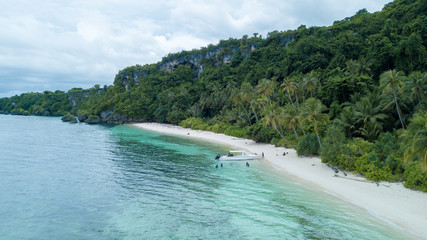 Aerial view of beautiful and clean beach with white sand beside blue ocean with nice sky