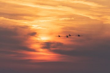 Fototapeta na wymiar Airplanes flying at sunset. Orange sky background