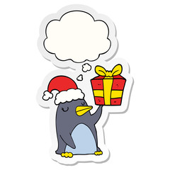 cartoon penguin with christmas present and thought bubble as a printed sticker