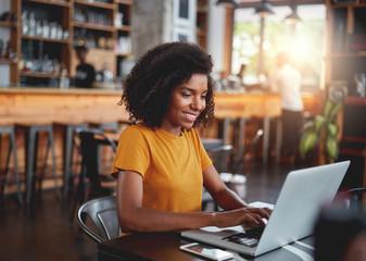 Young woman in café typing on laptop