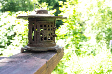 Vintage metal lantern. Retro lantern stands on the board against the background of the garden.