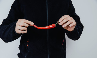 The man is holding a chili pepper in his hand. The concept of collecting vegetables and fruits. Using spices, vegetables for preparing meals.