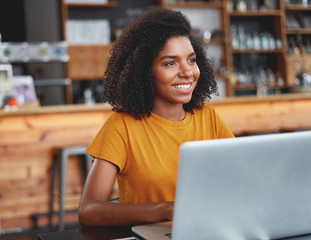 Smiling african woman with laptop in café