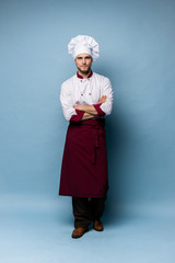 Full length portrait of cheerful joyful chef cook with stubble in beret and white outfit looking at camera isolated