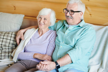 Happy retired couple in casualwear sitting on couch