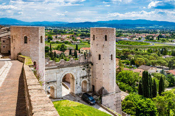 Fototapeta na wymiar The Porta di Venere, from the Roman era, made of white travertine, with its three arches and the two towers of Properzio. In Spello, province of Perugia, Umbria, Italy.