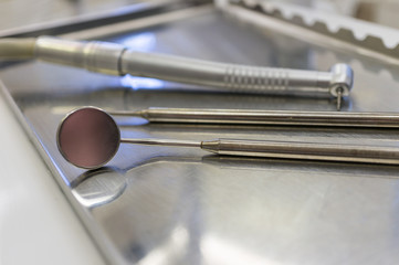 In the dental office - there is a dental handpiece and dental bur, a probe and a mirror on the metal stand of the dental unit. Dental treatment.