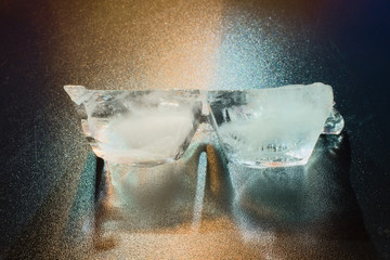 Two pieces of ice highlighted by different light sources.