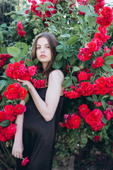 Close up summer portrait of young sensual interesting pretty young woman outdoors near red roses. Modeling, fashion, trendy, nature concept