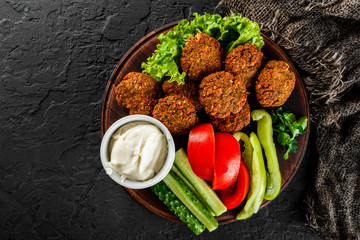 Roasted chickpeas falafel patties with garlic yogurt sauce, served with lettuce and fresh...
