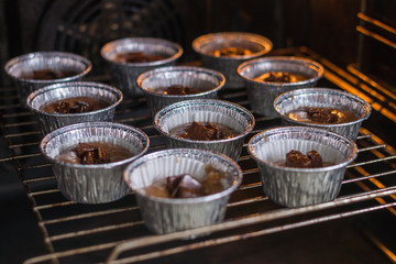 Raw muffins in the forms in the oven. Cooking chocolate muffins.