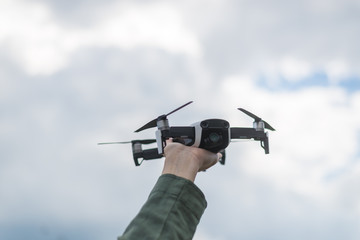 Flying drone in a female hand against the sky.