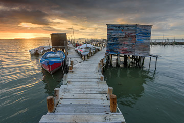 Sunset landscape of artisanal fishing boats in the old wooden pier. Carrasqueira is a tourist...