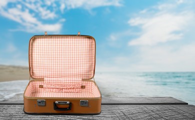 Retro suitcase with travel objects on wooden board on natural background