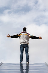 Young And Slim Man Observing From Above With Sky Background, Dressed In Casual Clothes