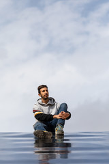 Young And Slim Man Observing From Above With Sky Background, Dressed In Casual Clothes