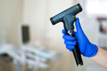 Professional equipment ophthalmologist ophthalmoscope..The doctor holds in his hand with a glove an ophthalmoscope..Blurred background
