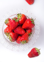 ripe strawberry in glass bowl around white.  flat lay