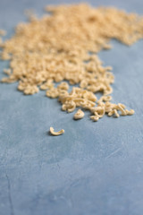 Homemade Small Macaroni Pasta Scattered on Blue Background