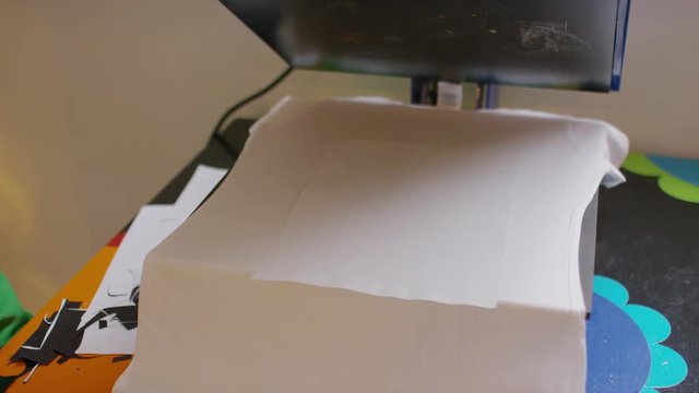 Young female removing her freshly printed tee shirt from the printing press