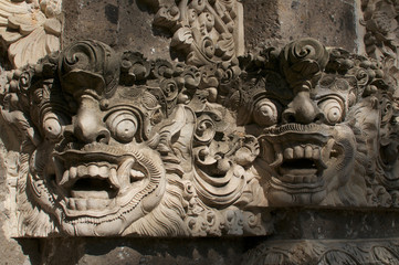 Beautiful Balinese masks engraved in a stone wall